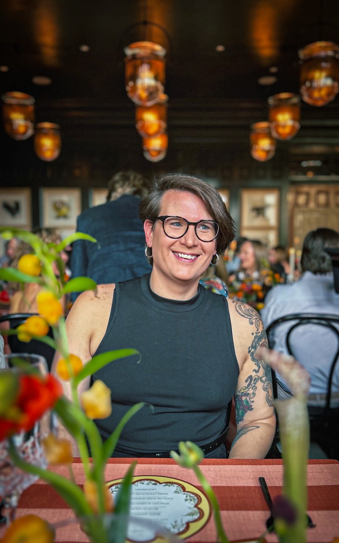 Portrait of a man with brown hair and glasses on a flat gray background.